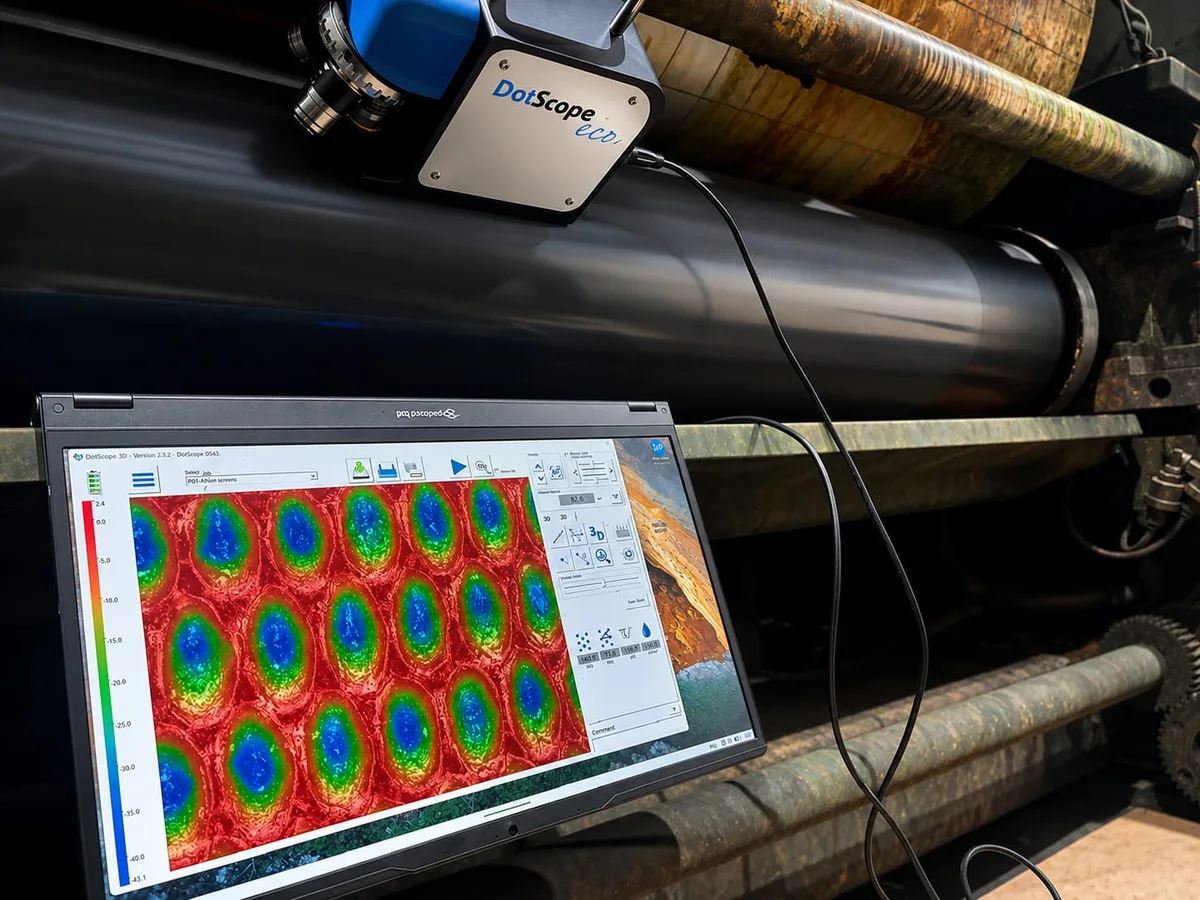Anilox roller inspection system mounted on a press, with cell volume data shown on a laptop